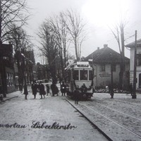 Bild vergrößern: Zu sehen ist eine Straßenbahn, die auf dem Marktplatz in Bad Schwartau hält. Fahrgäste steigen aus. Das Bild wurde in Schwarzweiß aufgenommen.