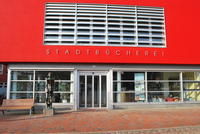 Bild vergrößern: Zu sehen ist der Eingangsbereich der Stadtbücherei, die Fassade ist in Rot gestrichen.