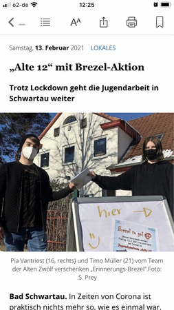 Bild vergr&ouml;&szlig;ern: Zwei Jugendliche stehen vor dem Gebäude der Stadtjugendpflege, halten Handzettel hoch, im Vordergrund steht ein Hinweisschild.