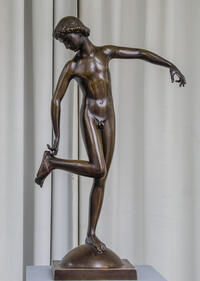 Bild vergrößern: Auf dem Foto ist eine Bronzestatue zu sehen. Ein Jüngling, der sich stehend an den rechten Fuß fasst.