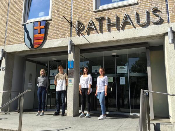 Das Bild zeigt vier Personen, die Auszubildenden der Stadt Bad Schwartau, vor dem Haupteingang des Rathauses der Stadt. 